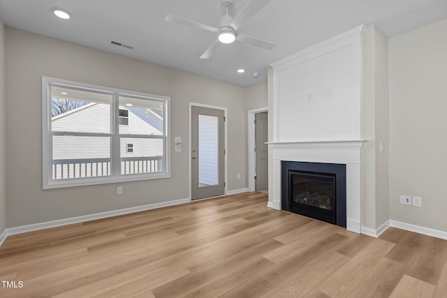 unfurnished living room featuring ceiling fan, a large fireplace, and light hardwood / wood-style floors