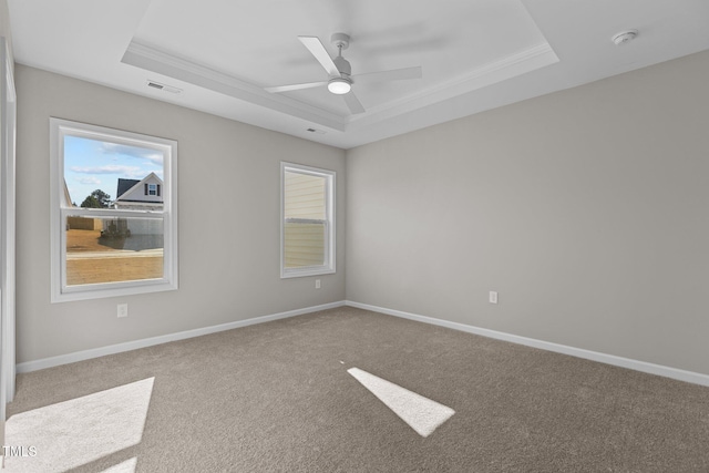 carpeted empty room featuring ceiling fan, crown molding, and a raised ceiling