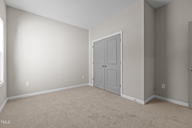 unfurnished bedroom featuring light carpet and a closet