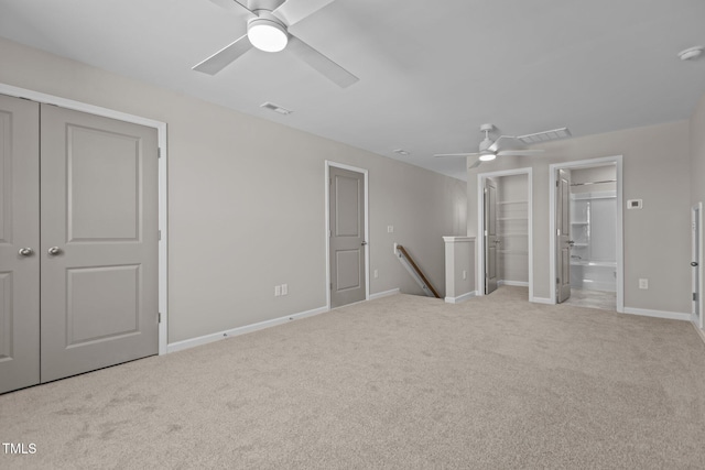 unfurnished bedroom with ceiling fan, light colored carpet, and ensuite bath