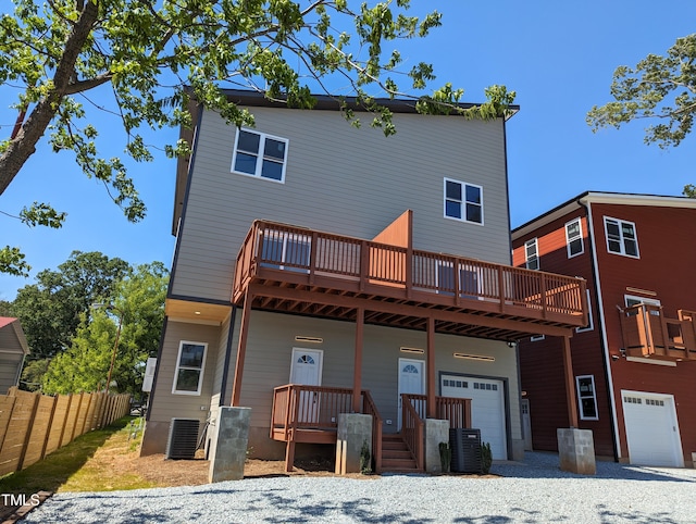 rear view of house with cooling unit, a garage, and a wooden deck