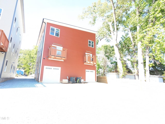 rear view of property featuring cooling unit and an attached garage