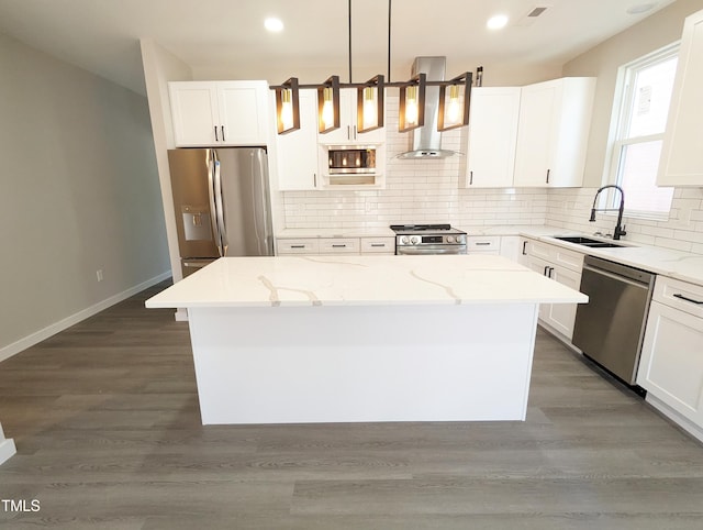 kitchen with a kitchen island, a sink, stainless steel appliances, wall chimney range hood, and backsplash