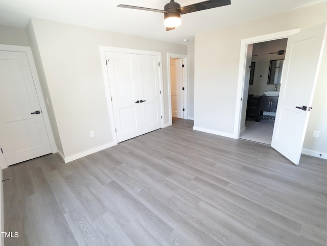 unfurnished bedroom with ensuite bathroom, ceiling fan, light hardwood / wood-style flooring, and a closet