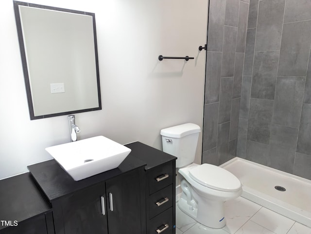 bathroom with tile patterned floors, toilet, vanity, and a tile shower