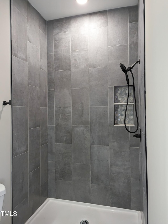 bathroom featuring toilet and a tile shower