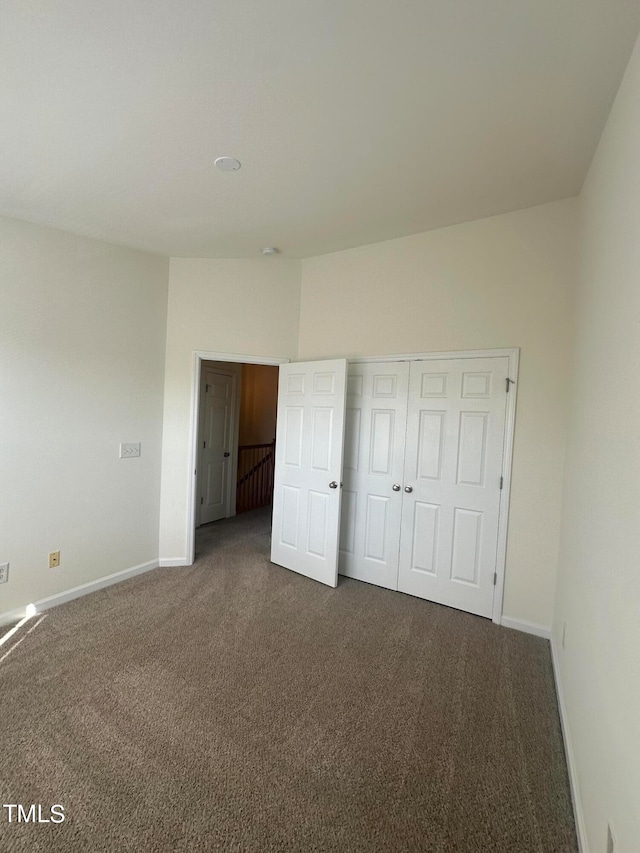 unfurnished bedroom with dark carpet and a closet