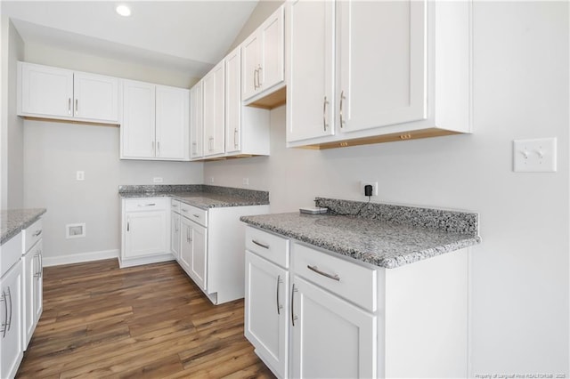 5411 Seedling Rd, Fayetteville, NC 28311 - kitchen with wood finished floors, white cabinets, recessed lighting, light stone counters, and baseboards