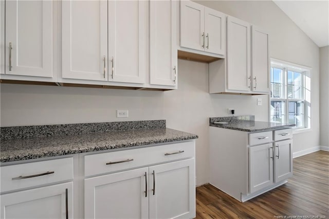 5411 Seedling Rd, Fayetteville, NC 28311 - kitchen with dark wood-style floors, dark stone countertops, white cabinets, and vaulted ceiling