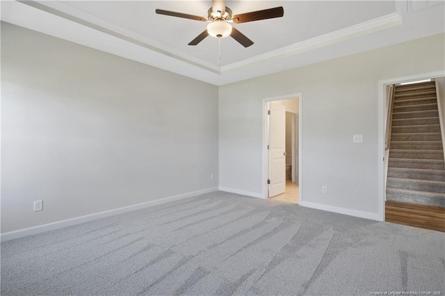 5411 Seedling Rd, Fayetteville, NC 28311 - carpeted empty room with a ceiling fan, baseboards, stairs, crown molding, and a tray ceiling