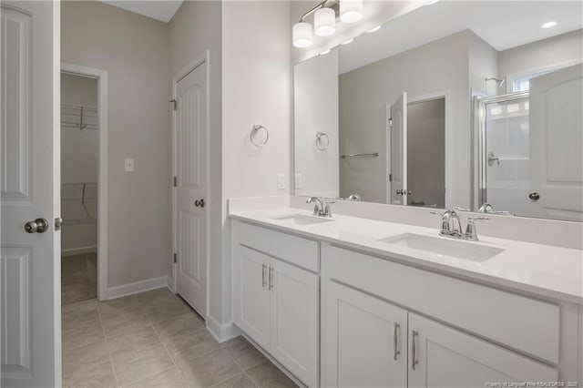 5411 Seedling Rd, Fayetteville, NC 28311 - bathroom with double vanity, a stall shower, a spacious closet, and baseboards
