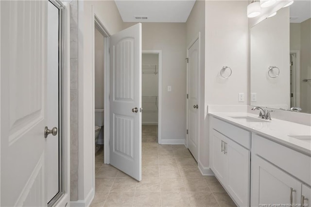 5411 Seedling Rd, Fayetteville, NC 28311 - full bath with double vanity, tile patterned flooring, toilet, a walk in closet, and baseboards