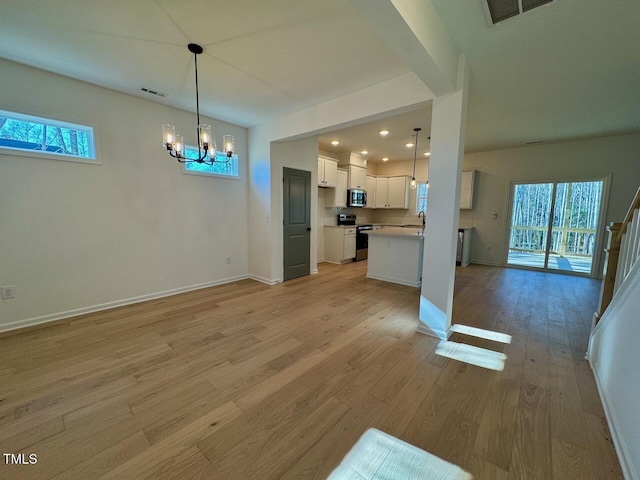 unfurnished living room with a notable chandelier, sink, and light hardwood / wood-style flooring