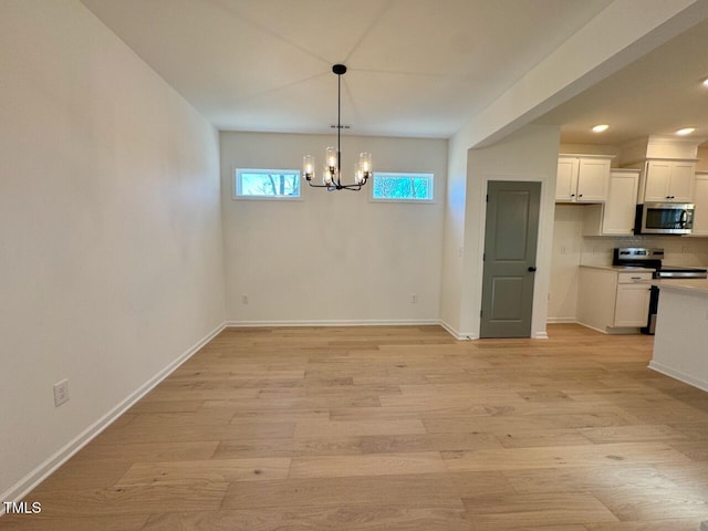 unfurnished dining area featuring light wood-type flooring and a notable chandelier