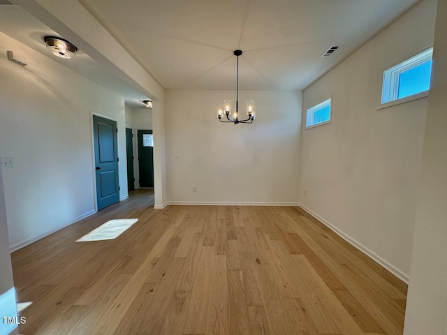 unfurnished dining area featuring light hardwood / wood-style floors and an inviting chandelier