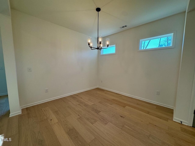 unfurnished dining area featuring a chandelier and light hardwood / wood-style flooring