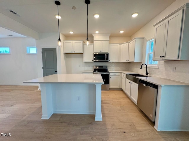 kitchen with white cabinetry, a kitchen island, stainless steel appliances, and decorative light fixtures