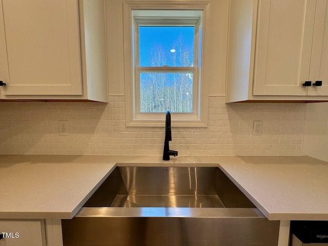 room details featuring decorative backsplash, white cabinetry, and sink