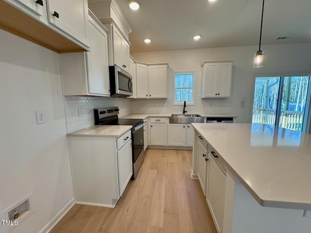 kitchen featuring white cabinetry, sink, hanging light fixtures, and appliances with stainless steel finishes