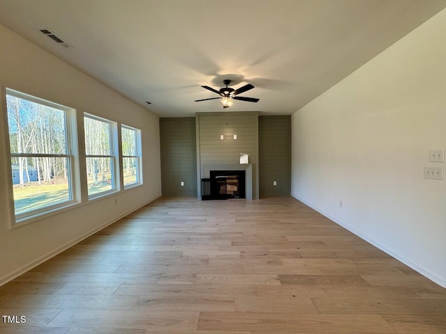 unfurnished living room with ceiling fan, a large fireplace, and light hardwood / wood-style floors