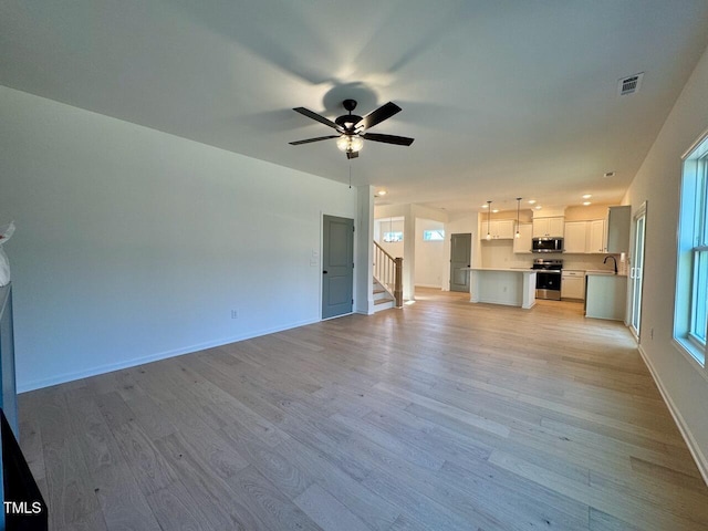 unfurnished living room with light hardwood / wood-style floors, ceiling fan, and sink