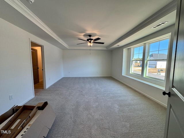 carpeted empty room featuring ceiling fan, a raised ceiling, and crown molding