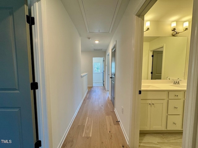 corridor featuring sink and light hardwood / wood-style floors