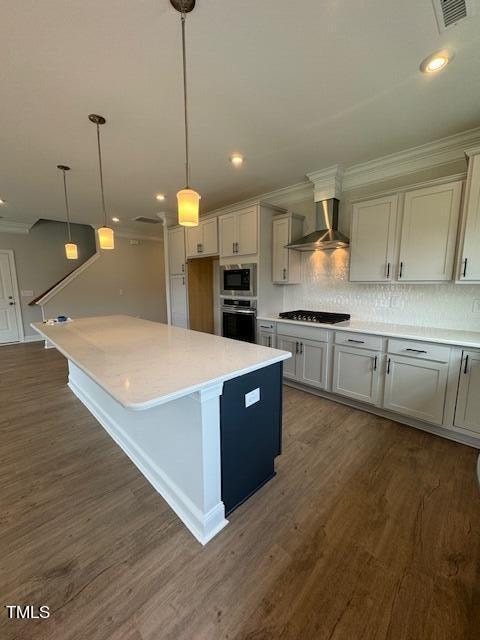 kitchen with appliances with stainless steel finishes, tasteful backsplash, hanging light fixtures, dark hardwood / wood-style floors, and wall chimney exhaust hood