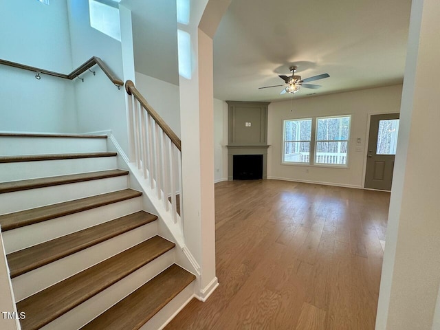 stairs with hardwood / wood-style floors and ceiling fan