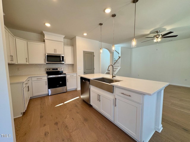 kitchen featuring an island with sink, appliances with stainless steel finishes, sink, and white cabinets