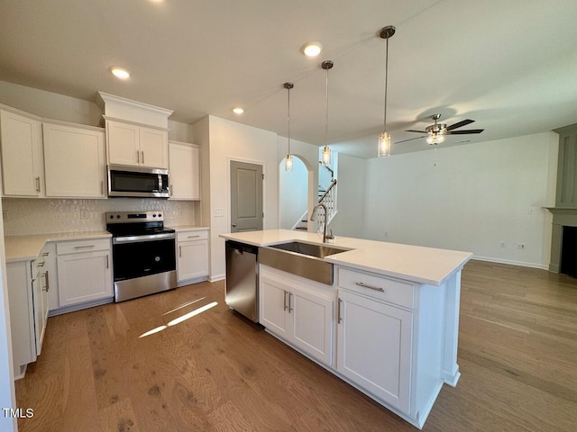 kitchen with a kitchen island with sink, sink, stainless steel appliances, and white cabinets