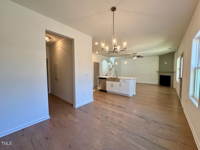 kitchen with hanging light fixtures, dishwasher, a kitchen island with sink, and light hardwood / wood-style flooring