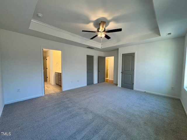 unfurnished bedroom with ornamental molding, a raised ceiling, and light carpet