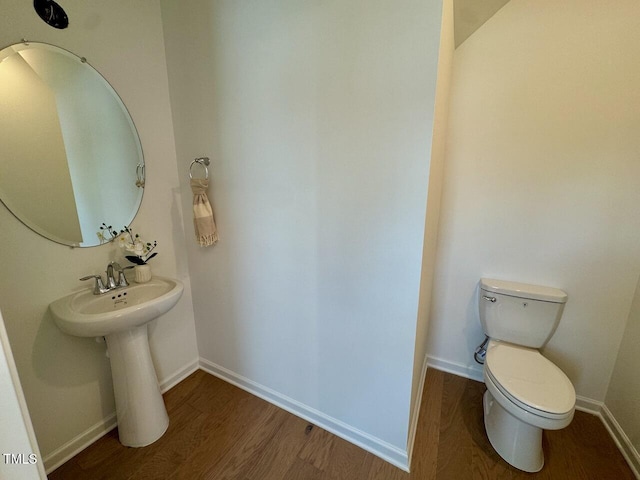 half bath featuring toilet, baseboards, and wood finished floors