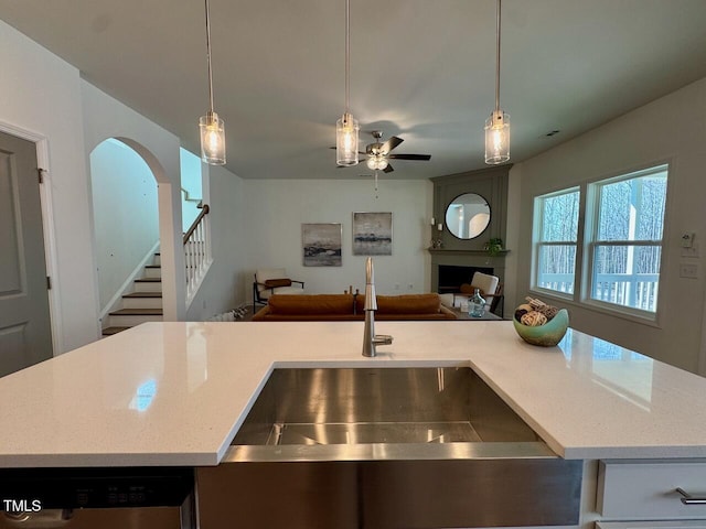 kitchen with open floor plan, decorative light fixtures, a sink, a fireplace, and stainless steel dishwasher