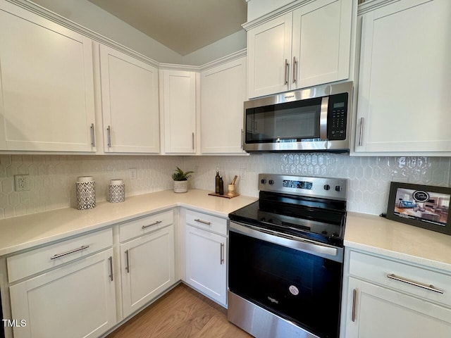 kitchen with decorative backsplash, light wood-style flooring, appliances with stainless steel finishes, light countertops, and white cabinetry