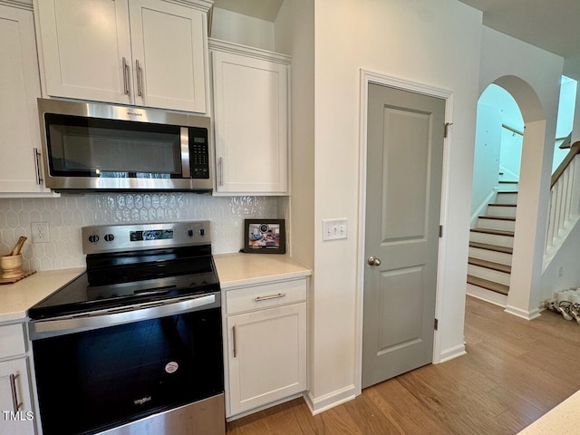 kitchen with light wood finished floors, backsplash, stainless steel appliances, and light countertops