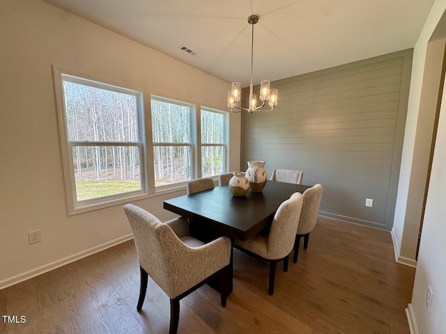 dining area featuring a notable chandelier, visible vents, baseboards, and wood finished floors