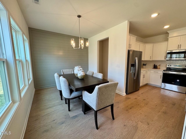 dining area with plenty of natural light, a notable chandelier, and light wood finished floors