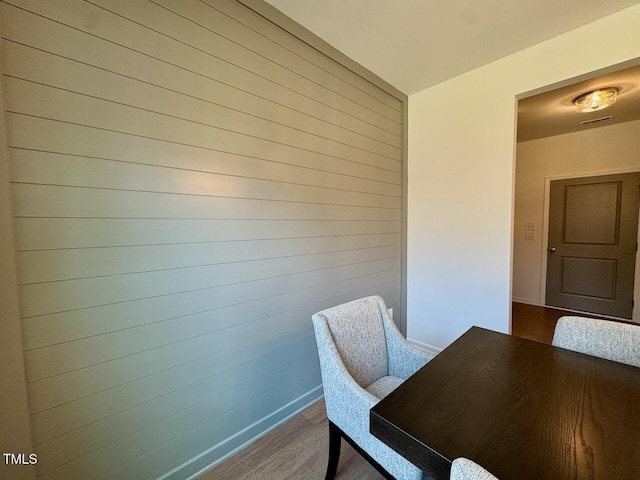 unfurnished dining area featuring dark wood-style floors, wood walls, and baseboards