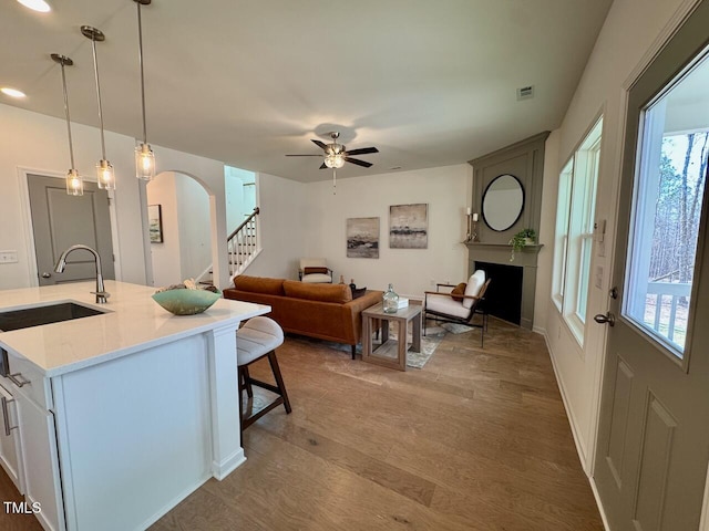 living area featuring visible vents, arched walkways, stairway, wood finished floors, and a fireplace