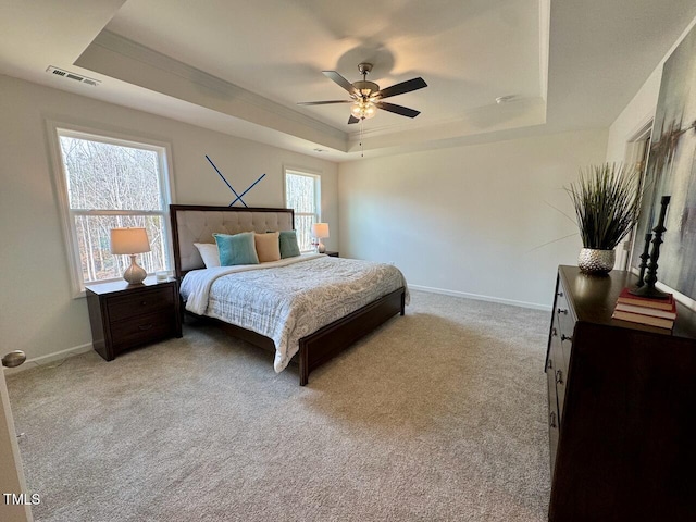 bedroom featuring light colored carpet, a ceiling fan, baseboards, visible vents, and a tray ceiling