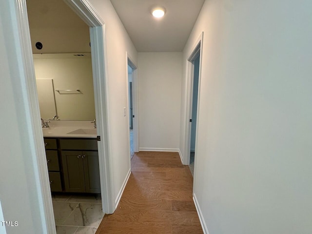 hallway featuring a sink and baseboards