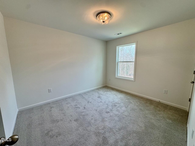 empty room featuring carpet flooring, visible vents, and baseboards