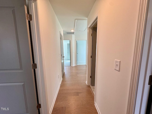 corridor featuring visible vents, light wood-style flooring, and baseboards