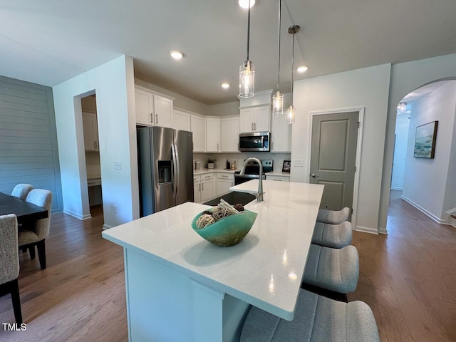 196 Grand Griffon Way, Lillington, NC 27546 - kitchen with stainless steel appliances, arched walkways, a kitchen breakfast bar, wood finished floors, and white cabinets