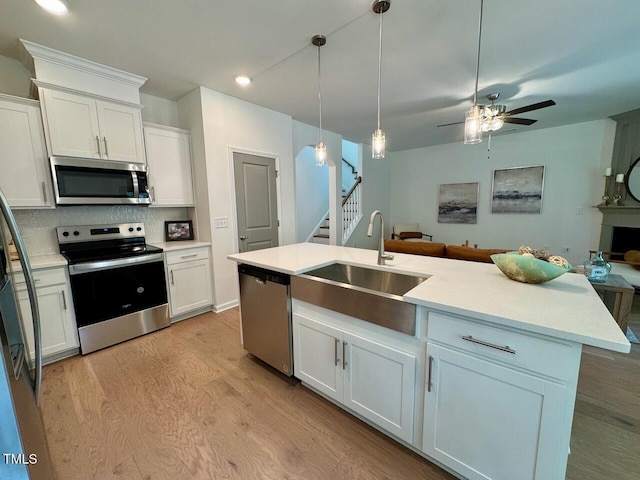 196 Grand Griffon Way, Lillington, NC 27546 - kitchen with stainless steel appliances, a sink, open floor plan, light wood-type flooring, and white cabinetry