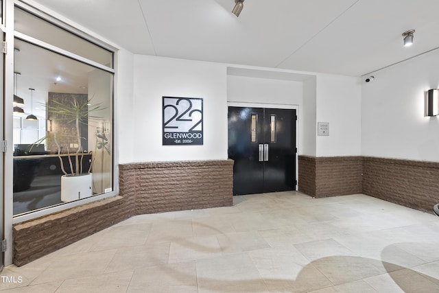 interior space with light tile patterned flooring and brick wall