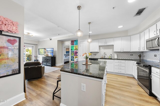 kitchen with dark stone counters, light hardwood / wood-style flooring, and white cabinets