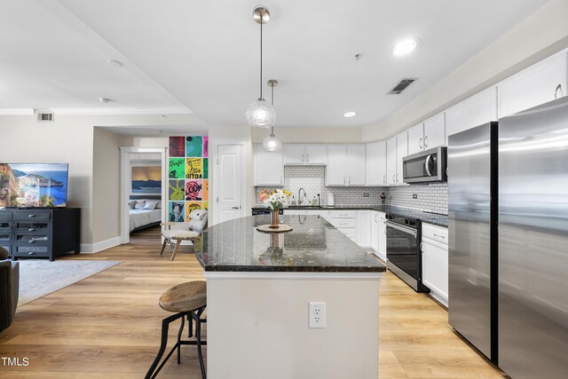 kitchen with light hardwood / wood-style floors, a center island, backsplash, and stainless steel appliances